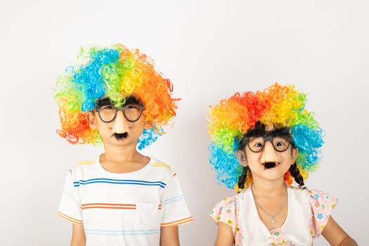 April Fool's Day. Two brothers funny kid boy and little girl clown wears curly wig colorful big nos and glasses and has mustache isolated on white background, Happy children festive decor