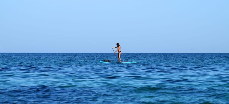 Varna, Bulgaria - September,7, 2020: A woman standing on a SUP board with an oar floats on the sea