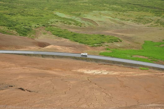 Aerial view of a car on a lonely road in a valley near the high-temperature area in Hverir, Iceland