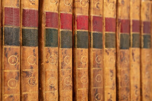 Pile of antique books with a leather cover and golden ornaments on a wooden table