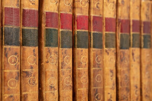 Pile of antique books with a leather cover and golden ornaments on a wooden table