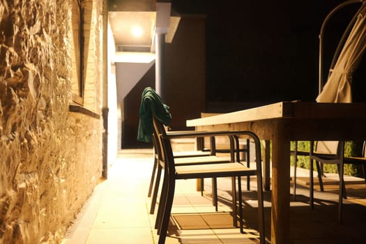 Wooden chair with swimming trunks over its back on a terrace in Burdinne, Belgium at night