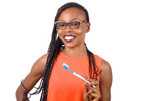 young girl standing in eyeglasses on white background smiling to hold a toothbrush in her hand.