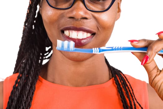 young girl standing in eyeglasses on white background smiling to hold a toothbrush to the mouth.
