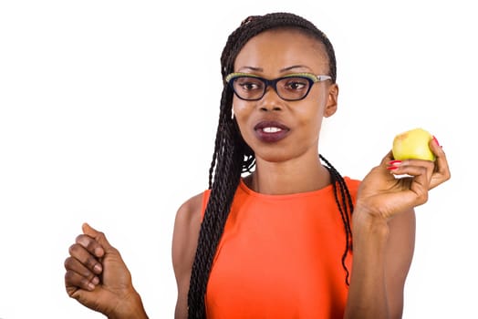 young girl standing in eyeglasses on white background smiling with apple in hand.