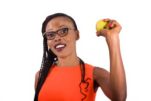young girl standing in eyeglasses on white background smiling with an apple in her hand.