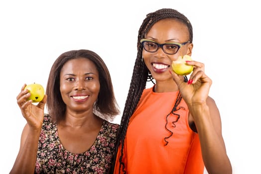 young women standing on white background showing apples while smiling on camera.