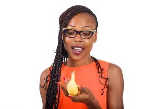 young girl standing in glasses on white background looking at a banana, surprise.