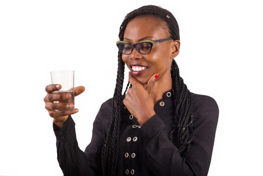 young woman standing on white background in glasses watching a drink while smiling.
