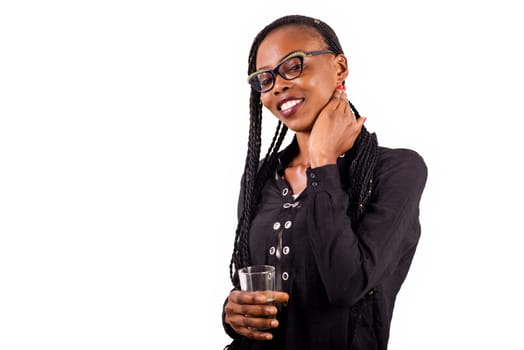 young woman standing on white background in eyeglasses to look at the smiling camera with glass of water in hand.