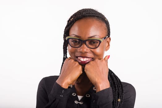 young african woman standing on white background looking at camera smiling hands under chin.
