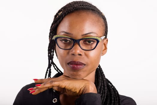 young african woman standing on white background looking at the camera with her hands under her chin.