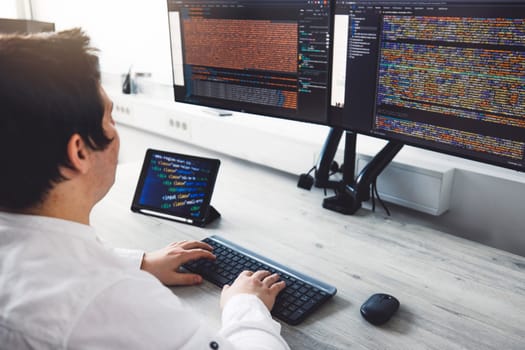 IT Programmer Working on Desktop Computer. Male Specialist Creating Innovative Software Engineer Developing App, Program, Video Game. Terminal with Coding Language. Over Shoulder. High quality photo