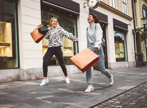 Two young caucasian women having fun on city street outdoors - Best friends enjoying a holiday day out together - Happy lifestyle, youth and young females concept. High quality photo