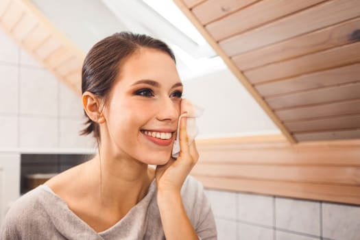 Beautiful young woman cleaning her face, removing make up with a cotton pad and micellar water. Skin care and beauty. Young beautiful woman cleaning her face. High quality photo