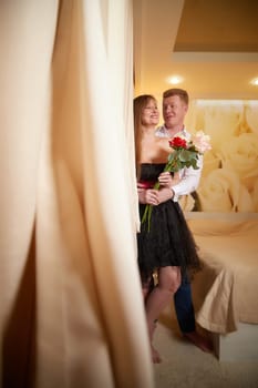 An adult couple of newlyweds in beautiful dress in a hotel room after the wedding. A guy and a girl, a man and a woman in beautiful room. The concept of love and care