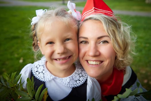 Young and adult schoolgirl on September 1. Generations of schoolchildren of USSR and modern Russia. Female pioneer in red tie and October girl in modern uniform. Daughter and Mother having fun