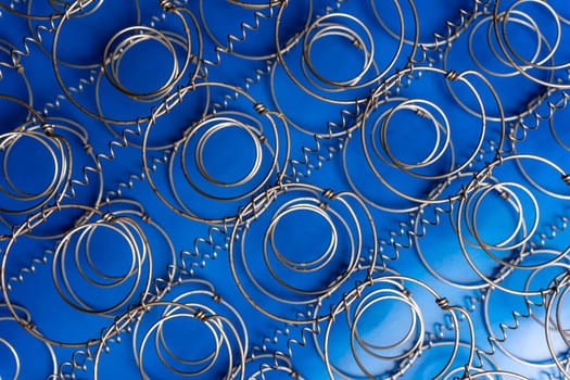 Abstract background The internal structure of a spring mattress. close-up of an old spring mattress on a blue background. Spring block. Sofa and bed. defocusing. top view