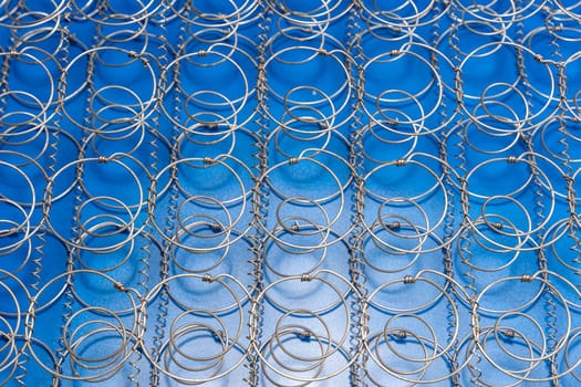 Abstract background The internal structure of a spring mattress. close-up of an old spring mattress on a blue background. Spring block. Sofa and bed. defocusing. top view