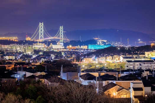 Suspension Bridge Towers Over Houses in Residential Neighborhood at Night. High quality photo