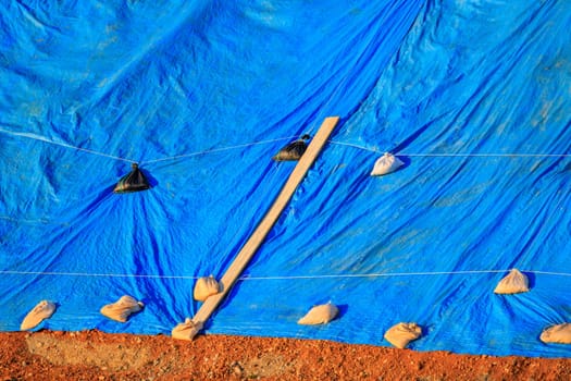 Blue tarp secured with sandbags protects materials from weather outdoors. High quality photo