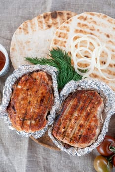 Grilled pork meat in foil with flapjack and vegetables. Summer rest concept