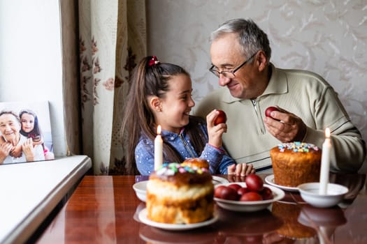 happy grandfather and granddaughter hold easter eggs in hand, folk game beats easter egg.