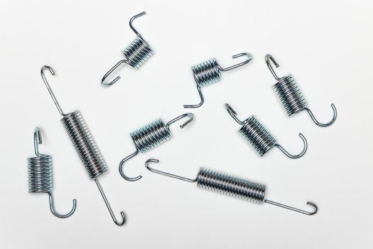 My metal springs on the table, machine repair parts. A set of spare parts for servicing vehicle calipers. Details on white background, copy space available.