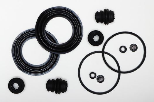 Rubber gaskets, rings, oil seals, machine repair parts. A set of spare parts for servicing the braking system of a vehicle. Details on white background, copy space available.