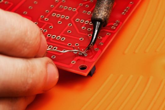 Soldering process on a red printed circuit board close up