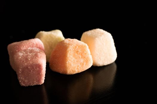 Small colorful sugar candy on a black background close up