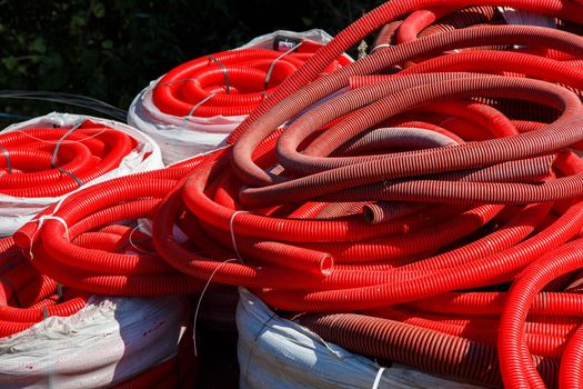 a pile of red corrugated PVC pipes for cable lay on the construction site, full frame background