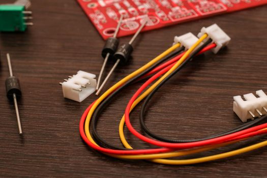 Colored wires, resistor and circuit board close-up on wooden table