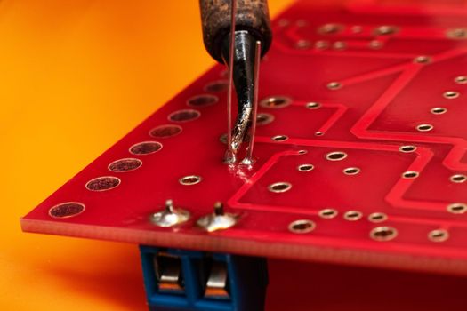 Soldering process on a red printed circuit board close up