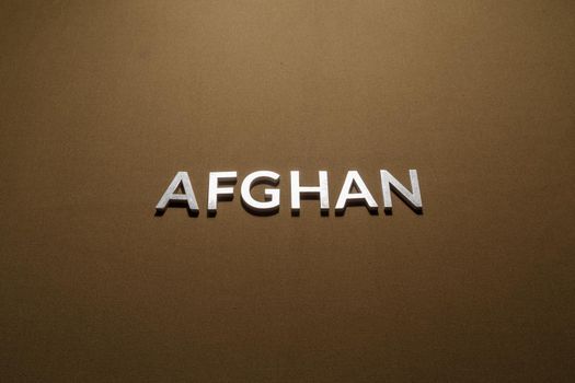 the word afghan laid with silver metal letters on tan khaki canvas fabric