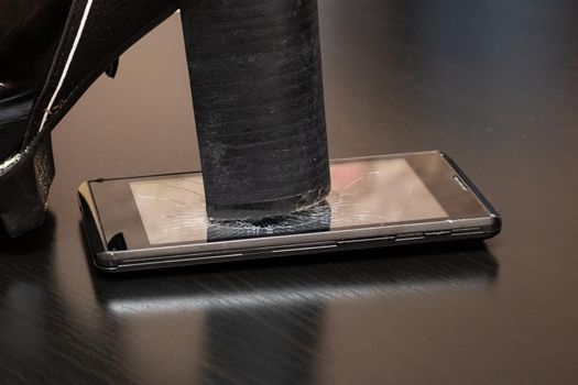 Broken screen telephone with heel shoes close up