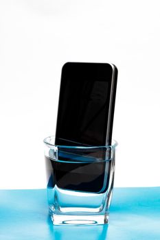 Mobile phone in a glass with water close up