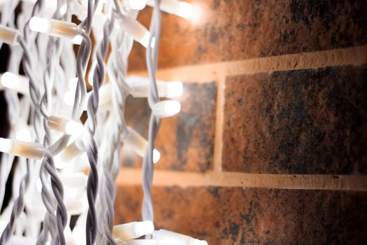 White light bulbs of a garland on a brick wall close up