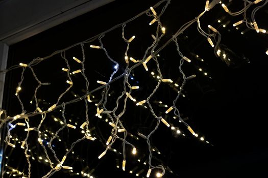 Yellow bulbs of a New Year's garland on a window in the night