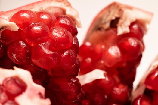 Sliced pomegranate with red grains close up, macro photo