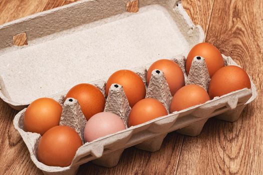 Chicken eggs in a cardboard box on wooden table close up