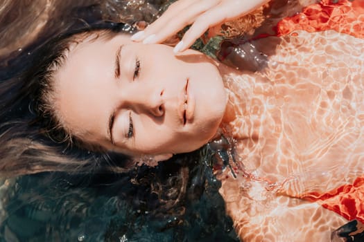 Side view a Young beautiful sensual woman in a mint long dress posing on a volcanic rock high above the sea during sunset. Girl on the nature on overcast sky background. Fashion photo