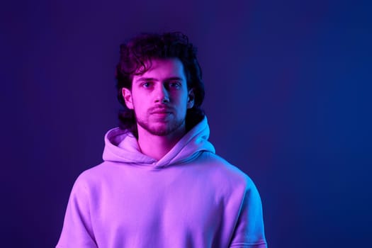 handsome bearded man in sweatshirt on blue background. Neon lighting