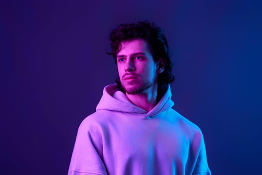 handsome bearded man in sweatshirt on blue background. Neon lighting