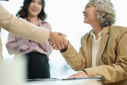 Asian entrepreneurs handshakes to congratulate the agreement between the two companies to enhance investment and financial strength. deal concept.