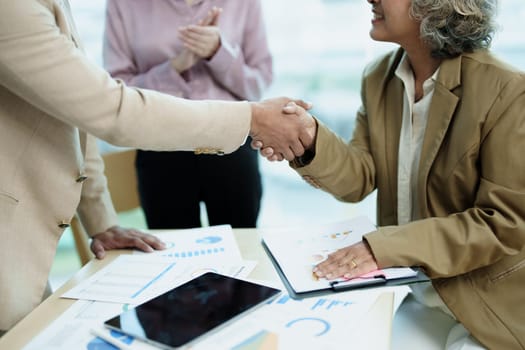 Asian entrepreneurs handshakes to congratulate the agreement between the two companies to enhance investment and financial strength. deal concept.