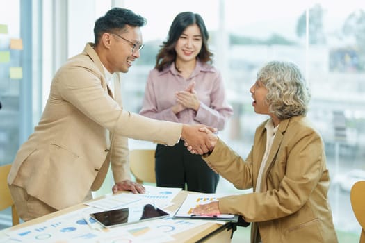 Asian entrepreneurs handshakes to congratulate the agreement between the two companies to enhance investment and financial strength. deal concept.