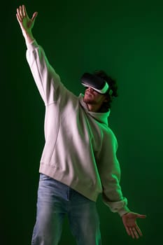 man in vr glasses and sweatshirt playing video games with his friends on green background. Neon lighting
