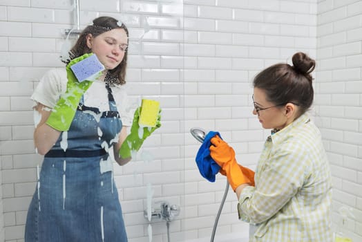 Family mother and teenage daughter cleaning together at home in the bathroom. Child helping parent, housekeeping, lifestyle, housework