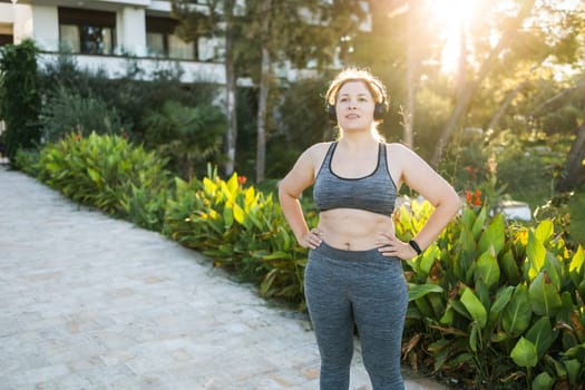 Fat woman and sports. Girl doing exercise for weight loss in the fresh air and laughing in camera after training.